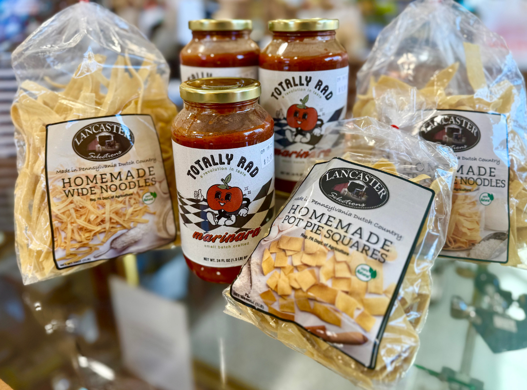 Homemade brittle and honey jars wrapped in clear gift bags on a blurred display table