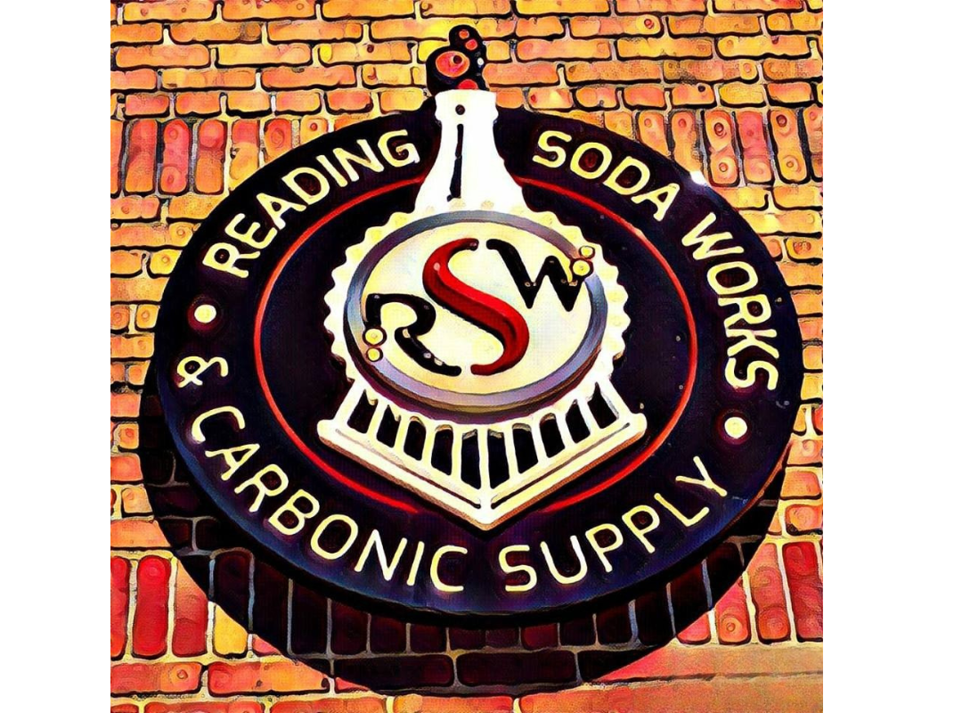 Round Reading Soda Works & Carbonic Supply sign on a brick wall, black circular logo with white and red lettering