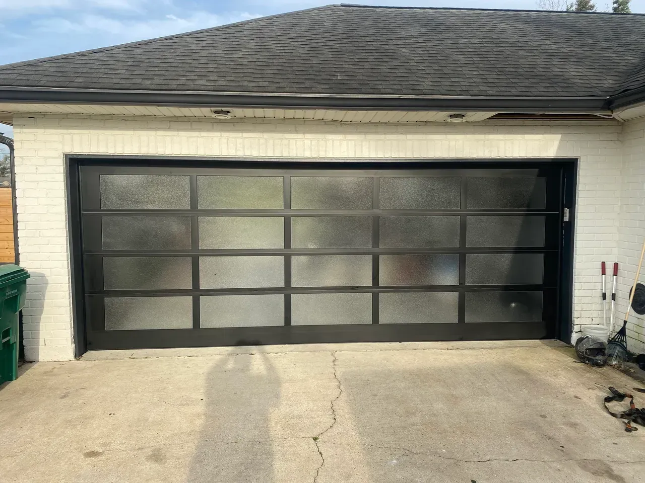 Black framed garage door with frosted glass panels on a white brick building.
