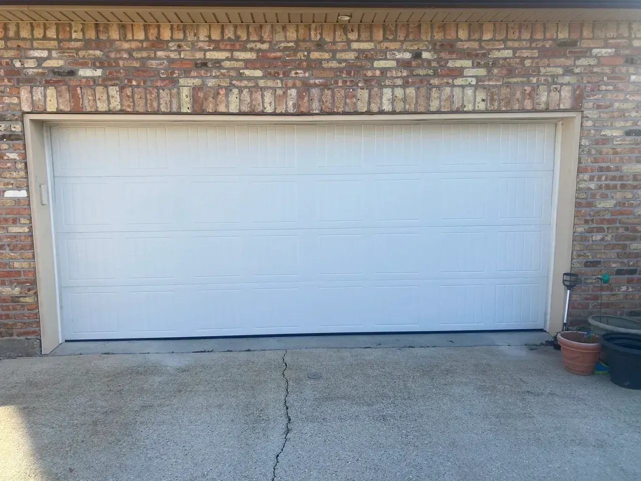White garage door on a brick building with a concrete driveway.