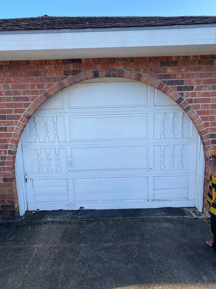 White garage door with an arched brick frame.