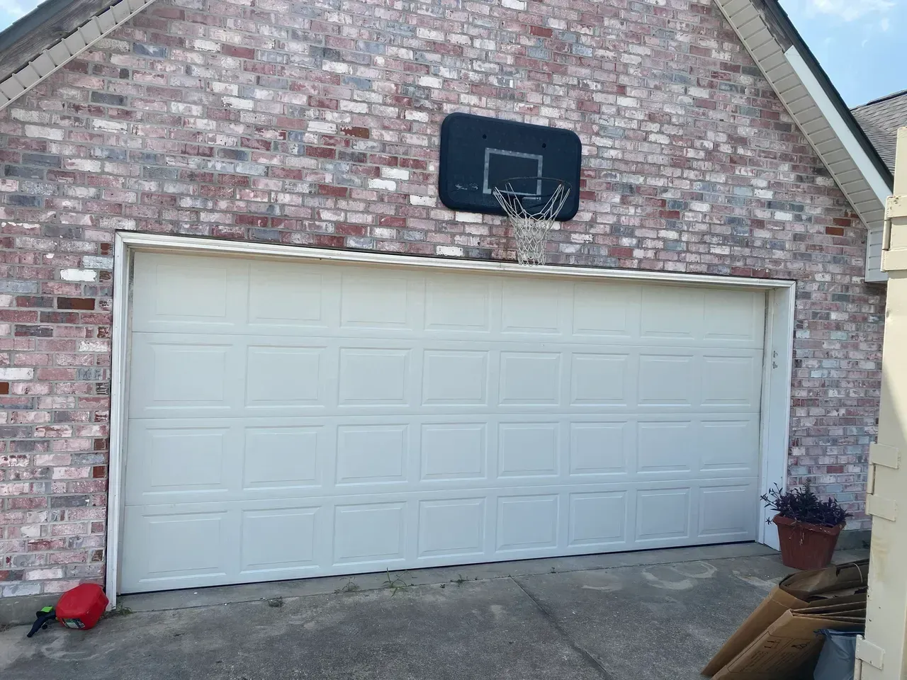Brick building with a closed white garage door and a basketball hoop mounted above.