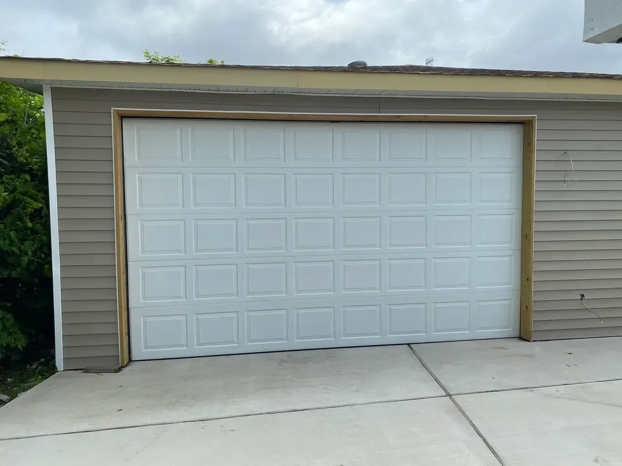 White garage door on a tan building with concrete driveway.