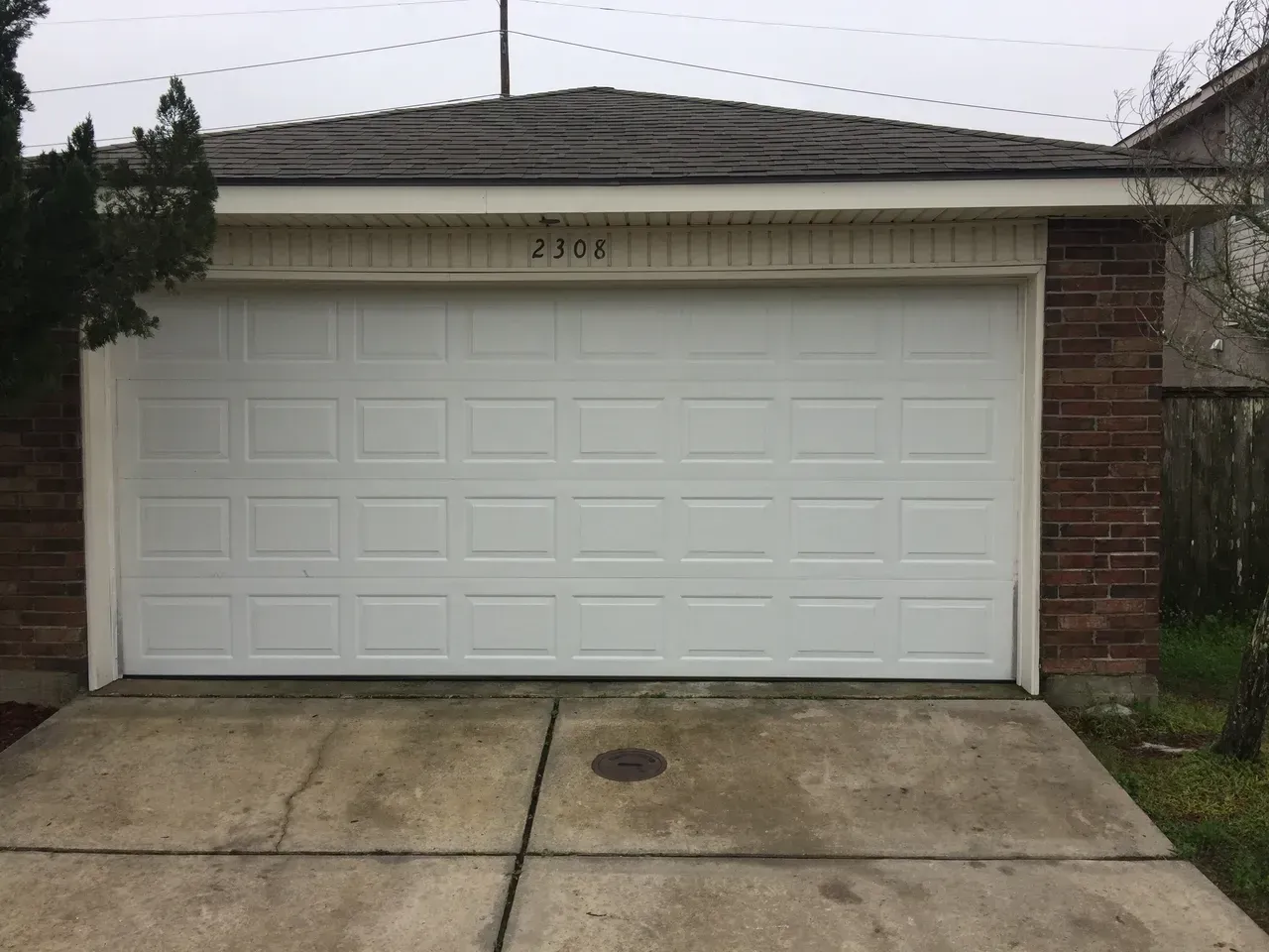 White garage door on a brick building with the number 2306 above it; overcast.