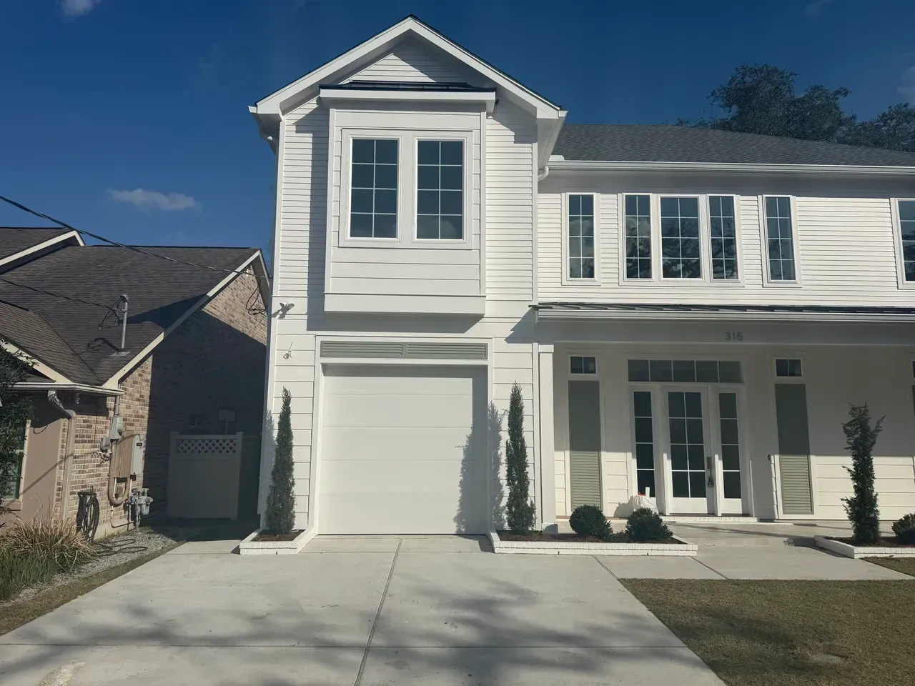 White two-story house with a garage and a small front yard, under a blue sky.