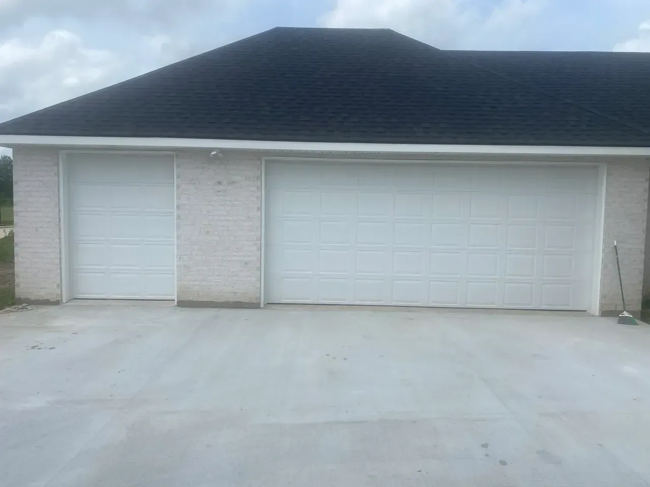 Garage with two white doors, set on a concrete driveway, under a dark roof.