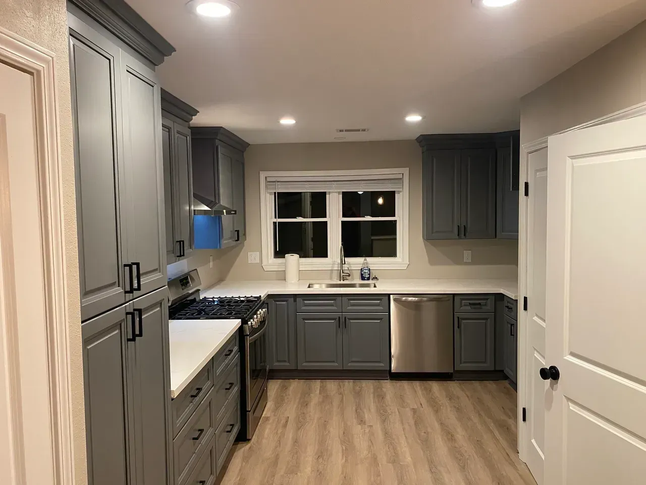 Gray kitchen with light-colored countertops, cabinets, and stainless steel appliances. Hardwood-style floors.