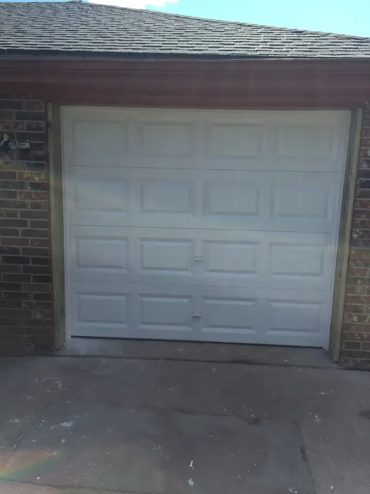 White garage door on a brick building with a concrete driveway.