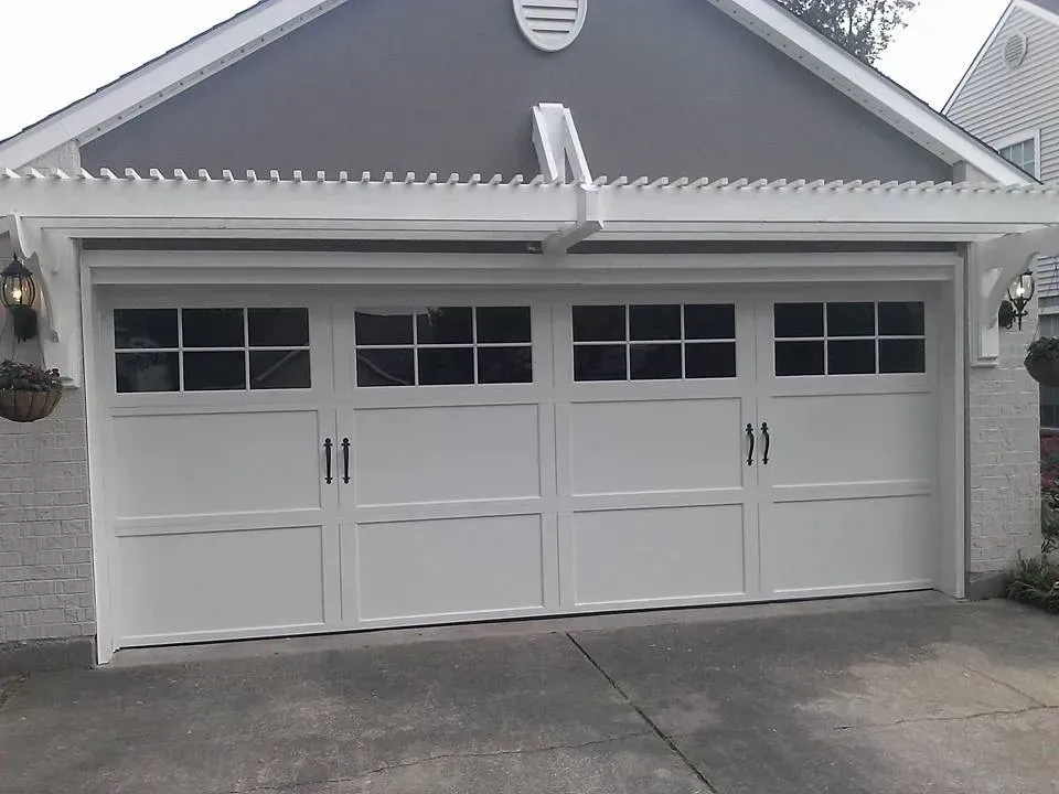 White garage door with windows, black handles, and pergola.