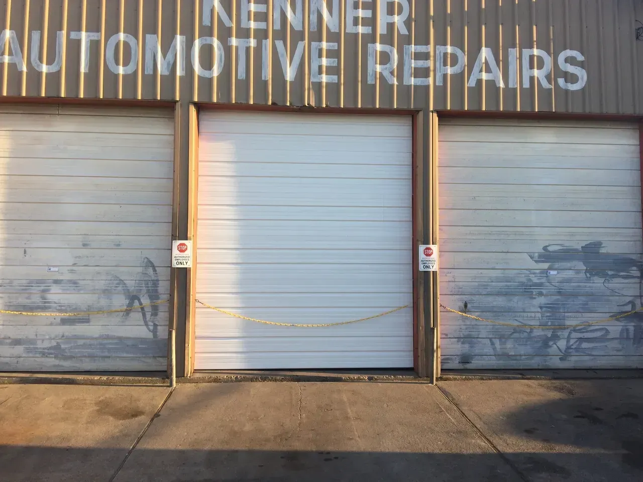 Kenner Automotive Repairs building with closed garage doors, some damage to the lower walls.