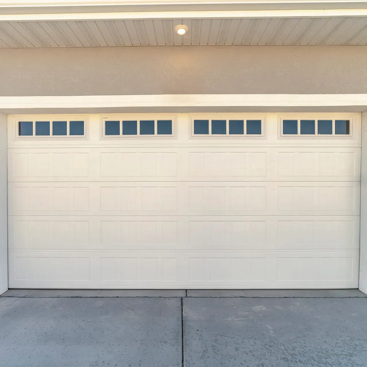 White garage door with windows above, on a concrete driveway.