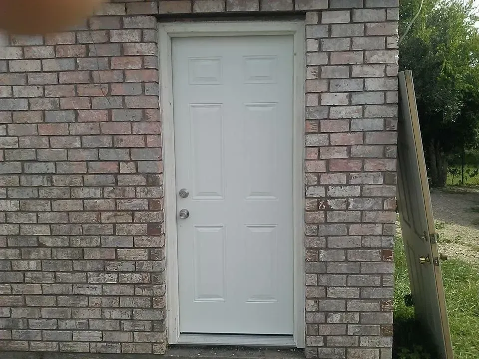 White door in a brick building. The door has a silver handle and knob.
