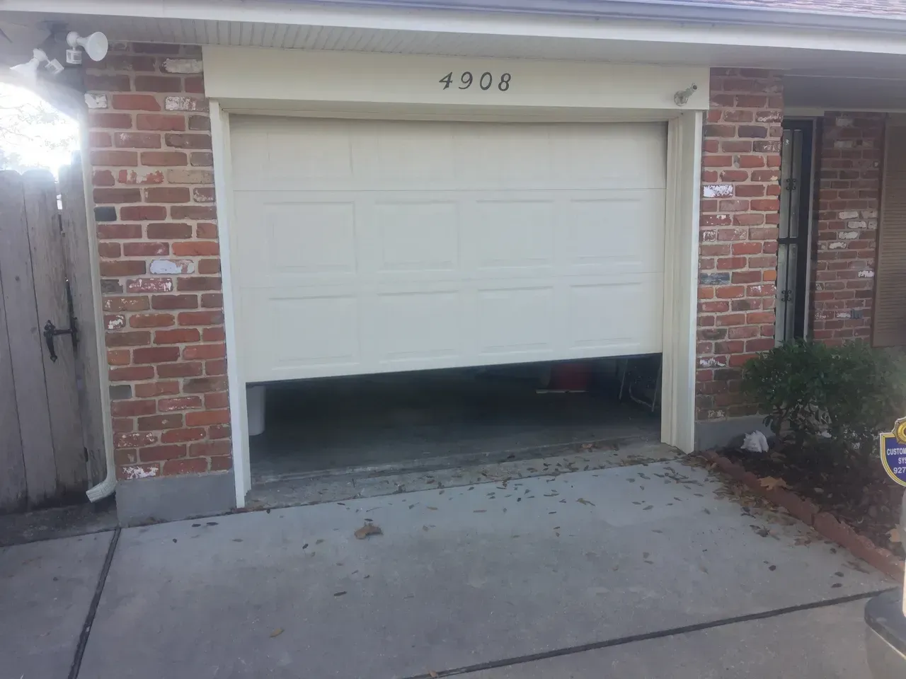 Partially open garage door on a brick building; the number 4906 is above the door.