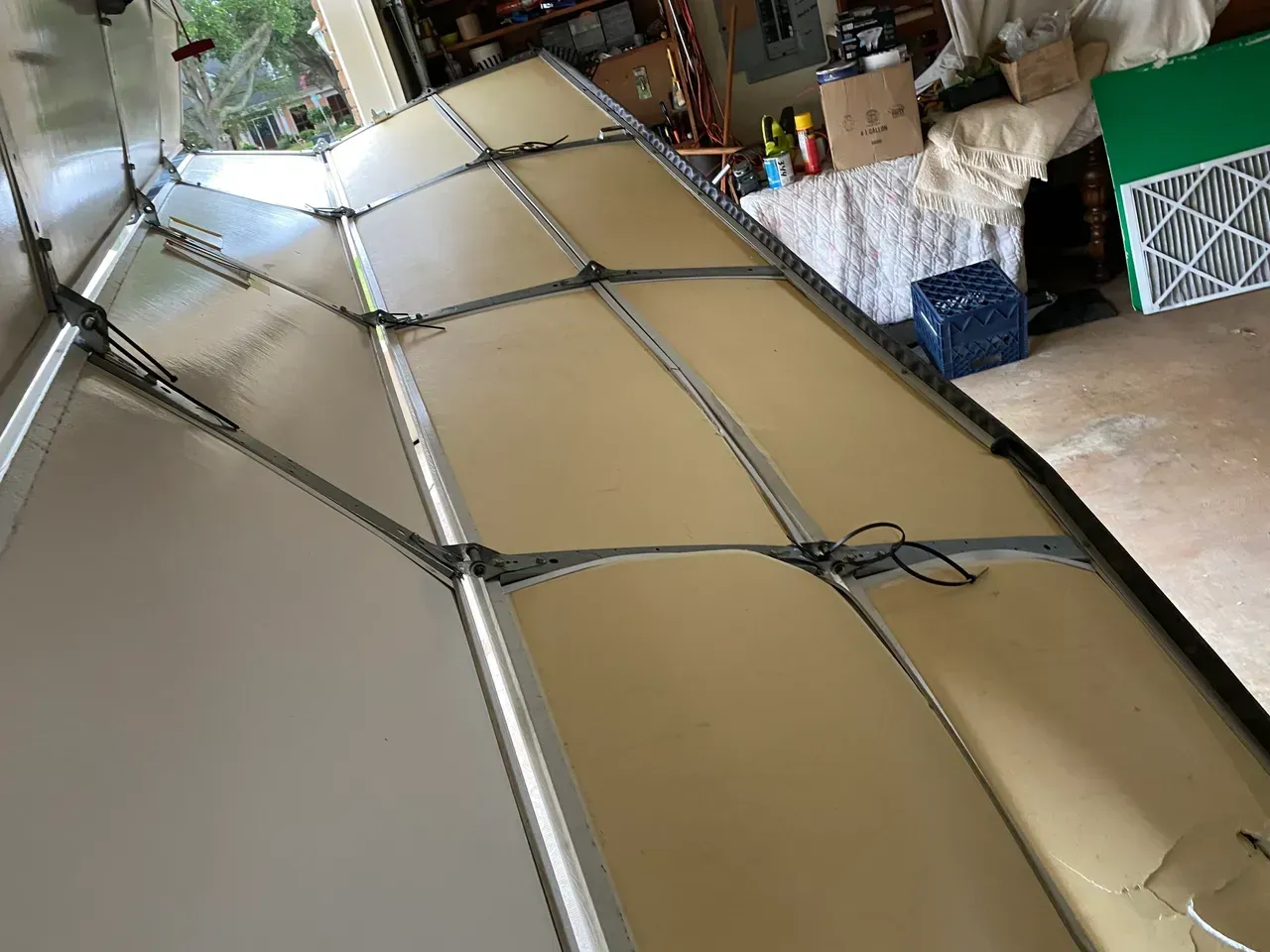 Tan and silver vehicle roof with grid of gray supports, in a garage.