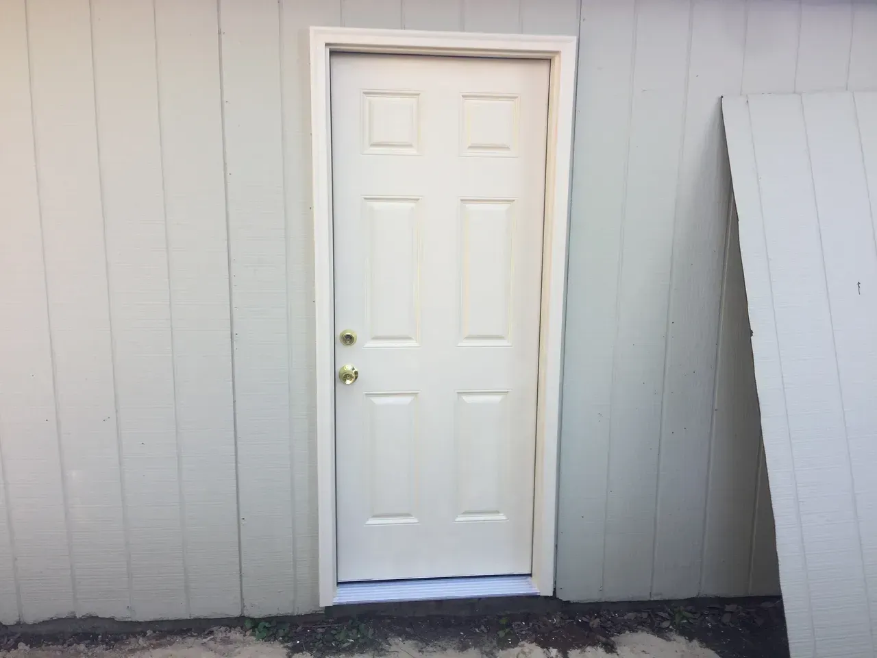 White door with a six-panel design, set in a light beige wall with white trim.