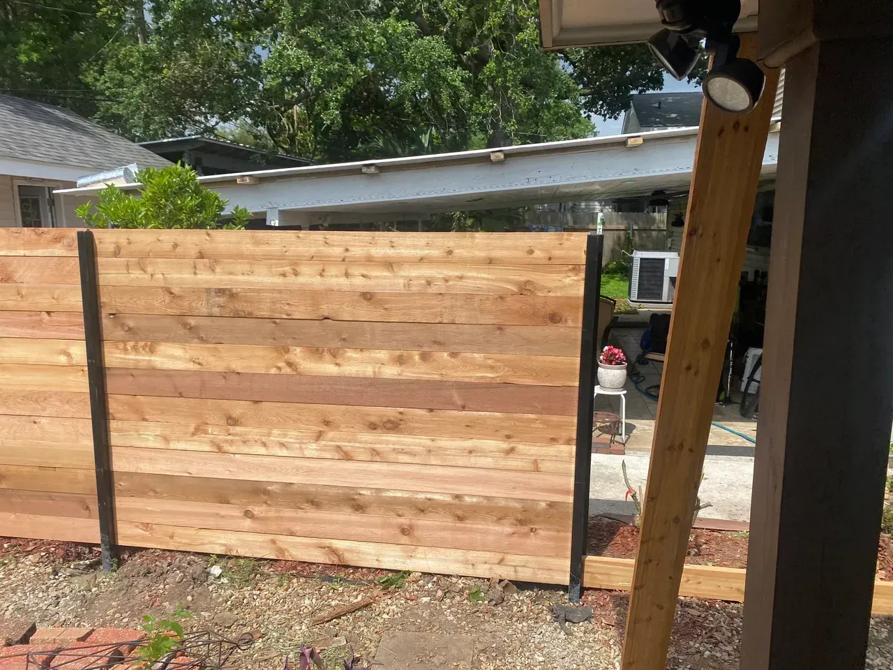 Wooden horizontal fence with black posts; backyard setting.