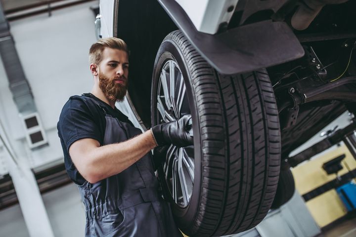 A man is changing a tire on a car in a garage.