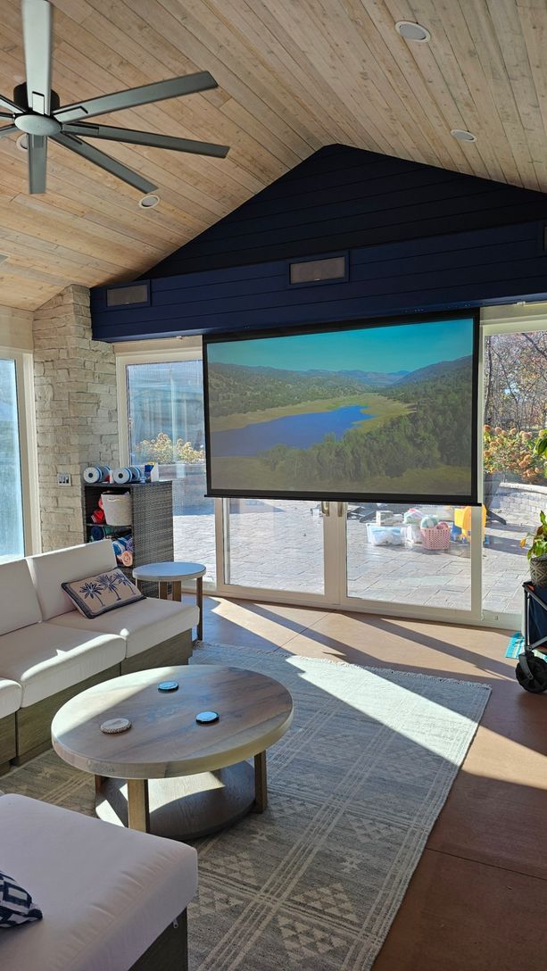 A living room with a projector screen and a ceiling fan.