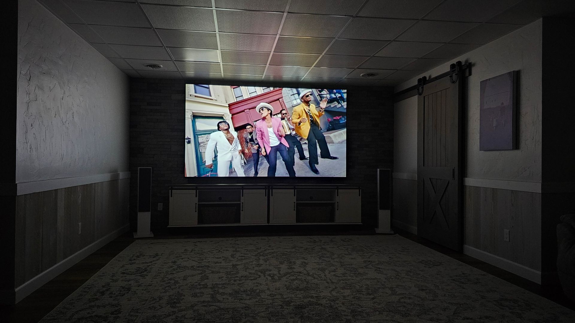 A group of people are standing in front of a large screen in a dark room.