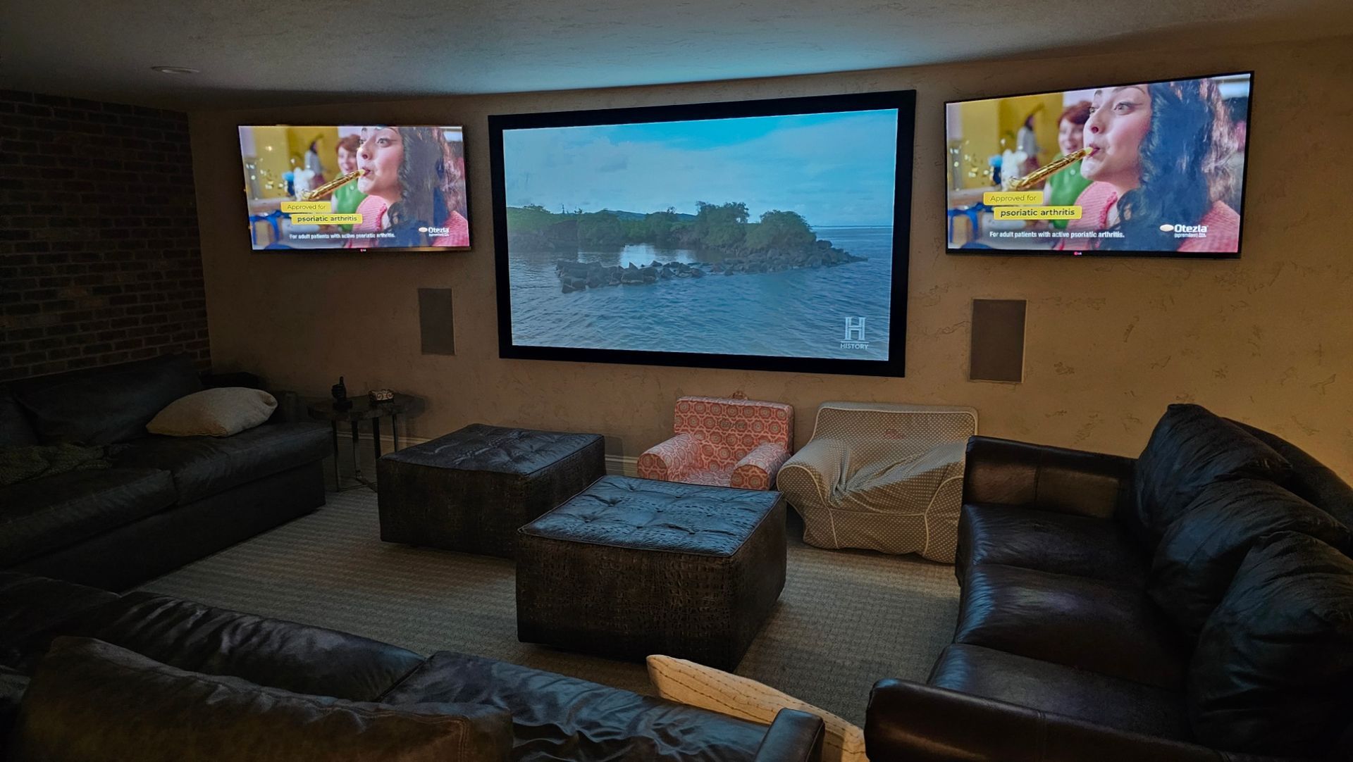 A living room with two flat screen tvs and a projector screen.