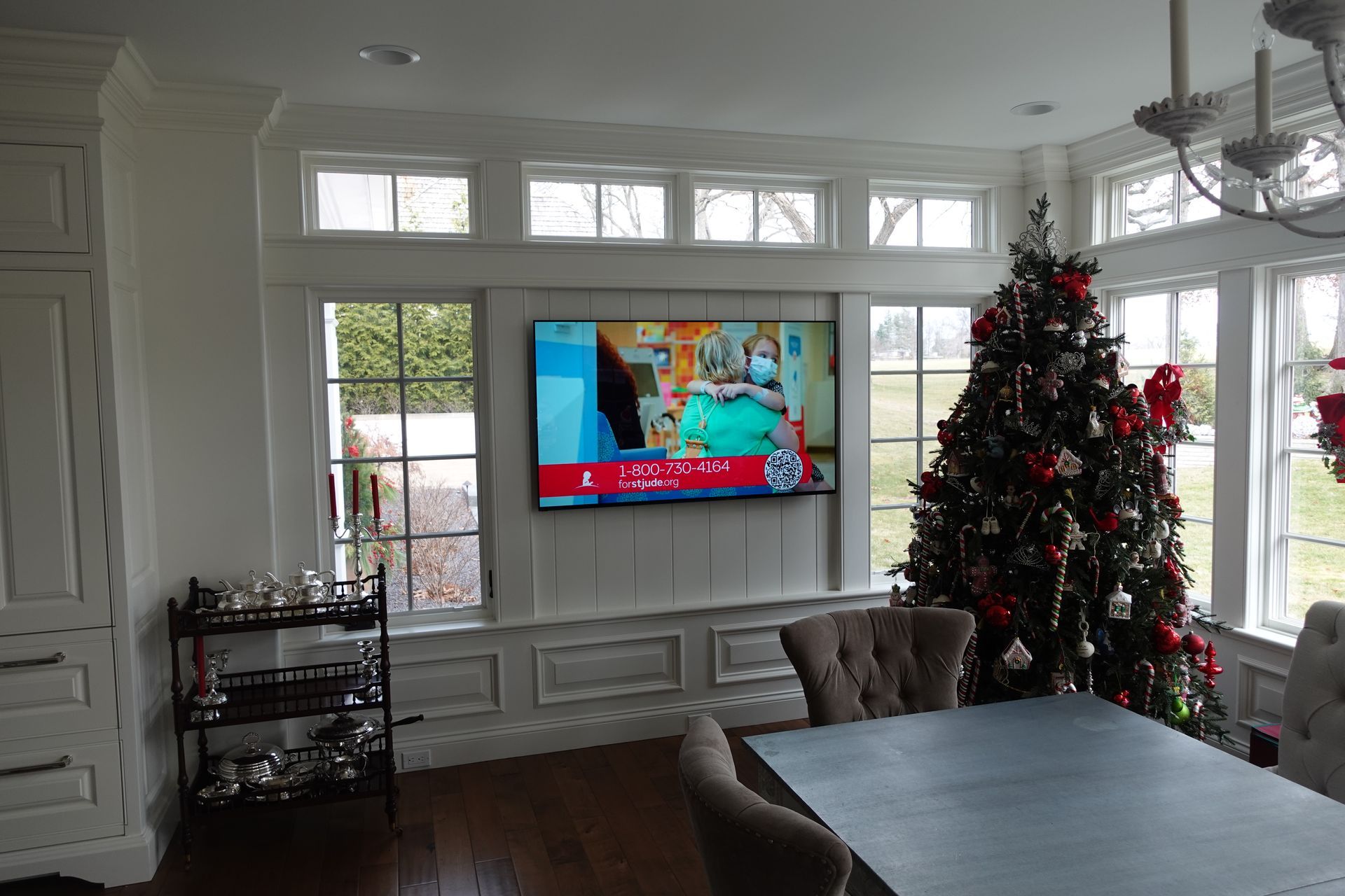 A dining room with a christmas tree and a flat screen tv