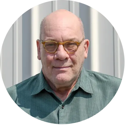 A bald man wearing glasses and a green shirt is in a circle.