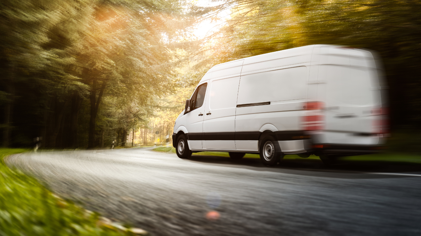 A white van is driving down a country road.