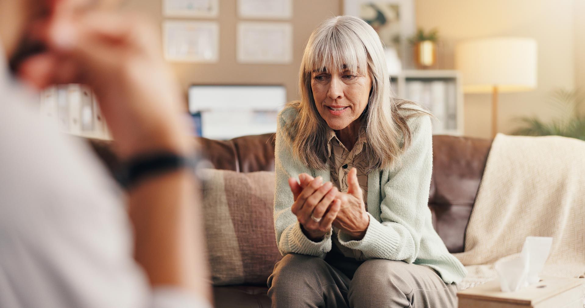 Therapist speaking with a seated client on a sofa in a bright living room