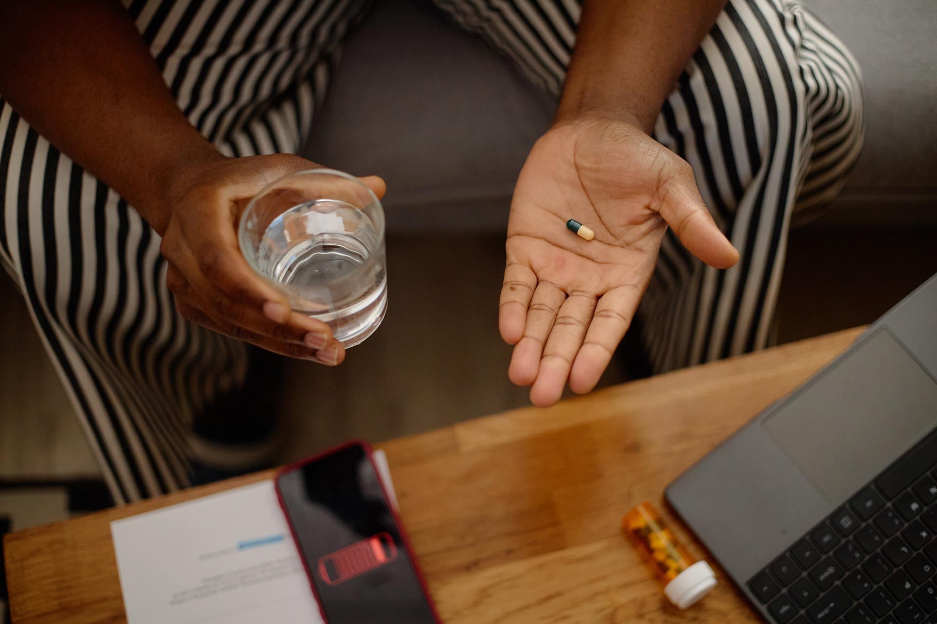Person holding coins in open palm beside a laptop and notebook on a desk
