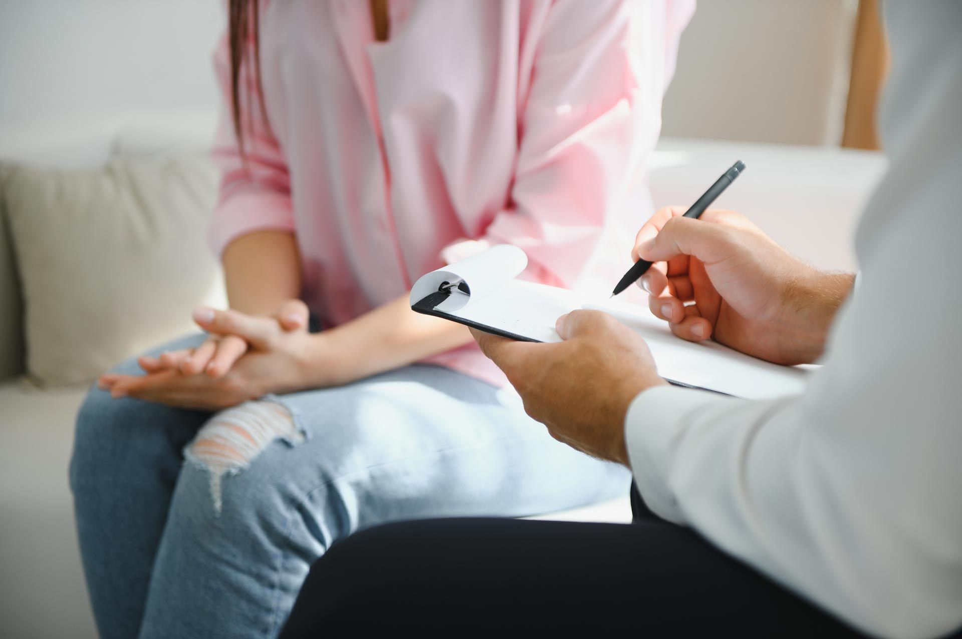 Therapist taking notes during a counseling session with a seated client