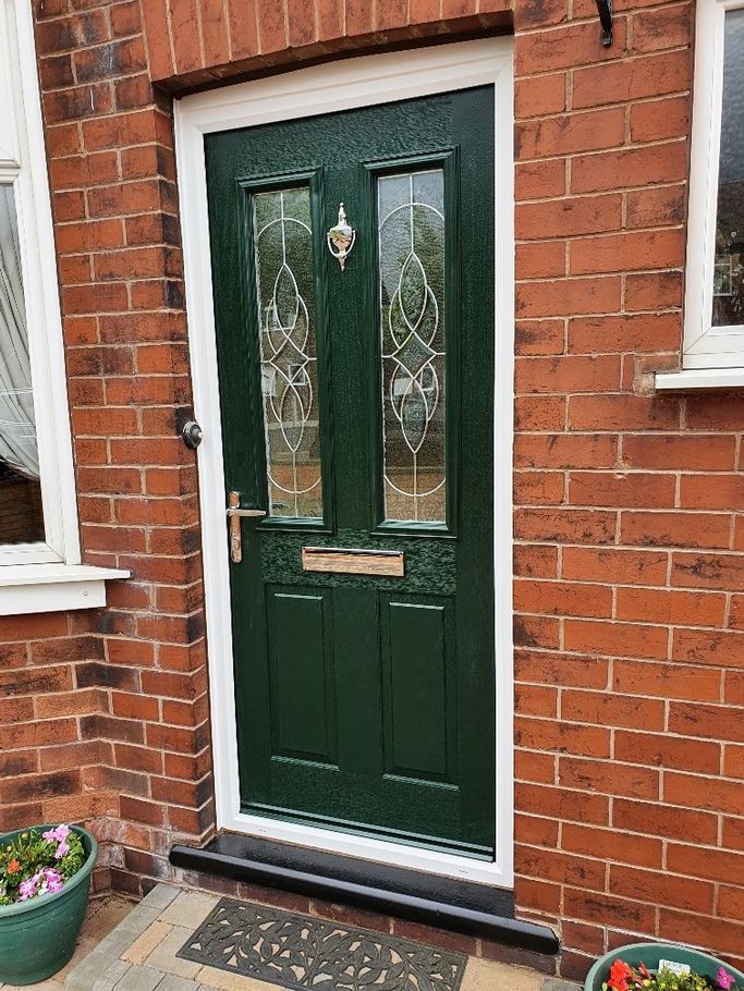 A green front door is on a red brick building.