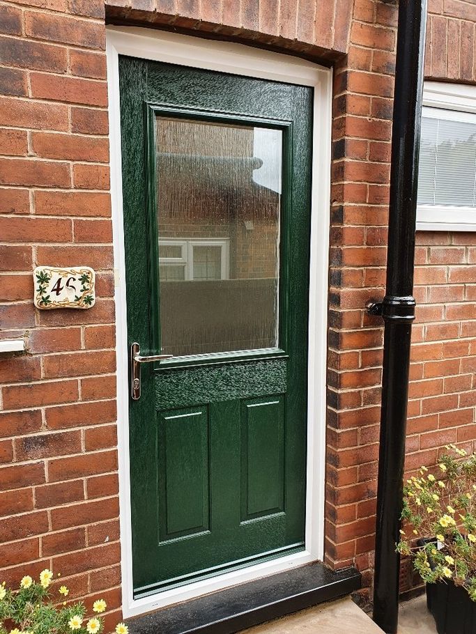 A green door is on a brick wall 