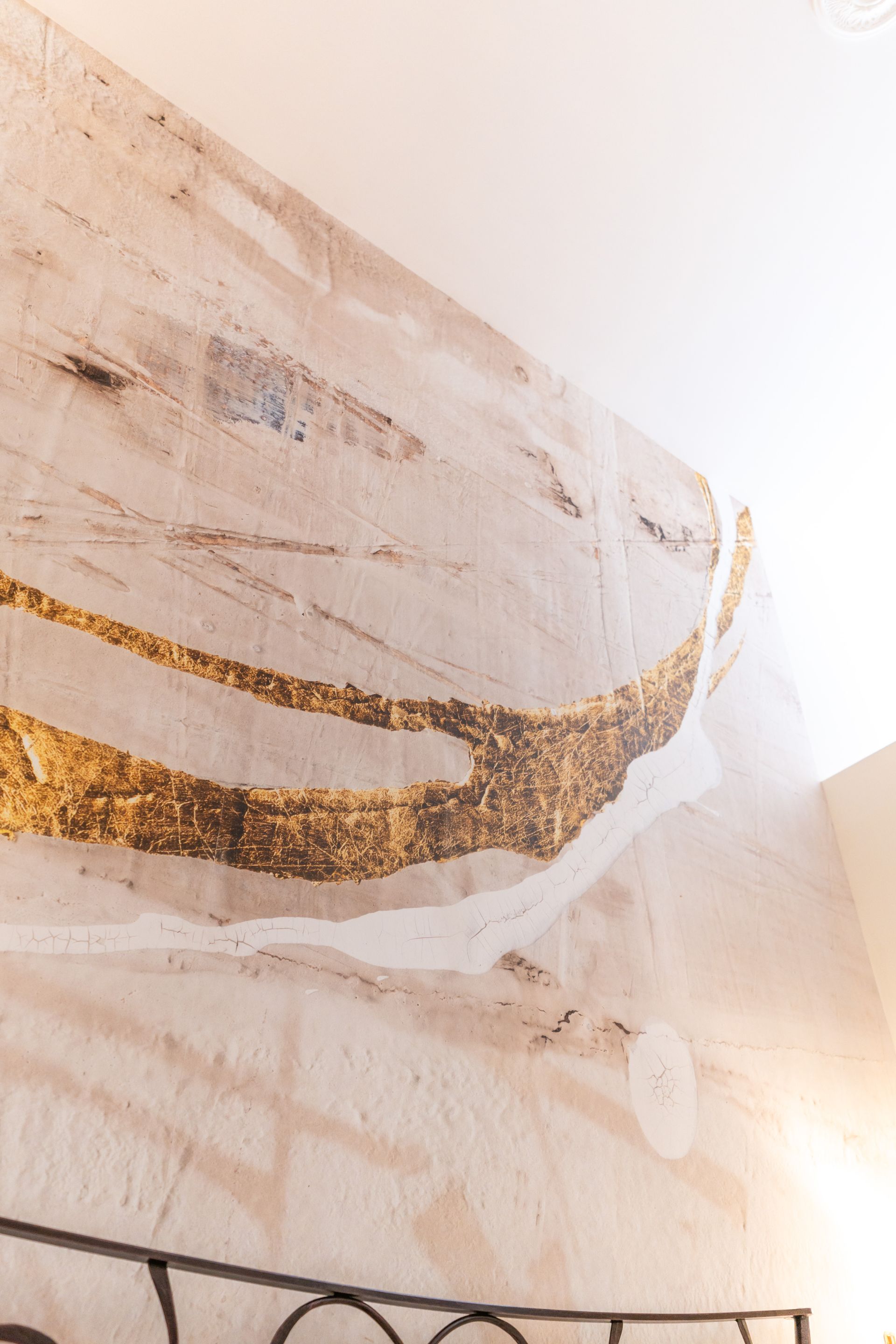 Strukturierte, cremefarbene Wand mit goldenem Mosaikmuster; Inneneinrichtung.