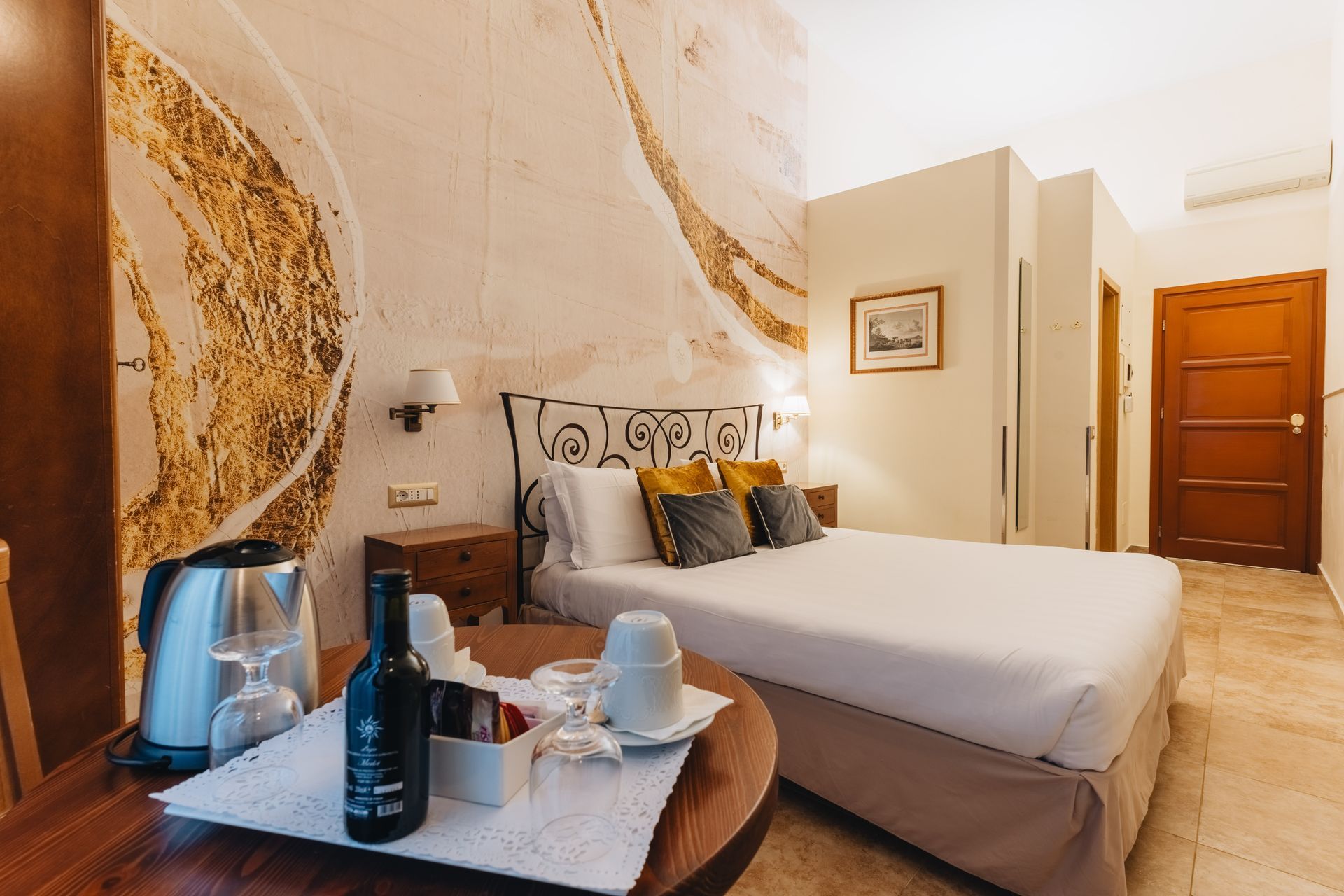 Hotel room with bed, table with drinks, and a decorative wall.