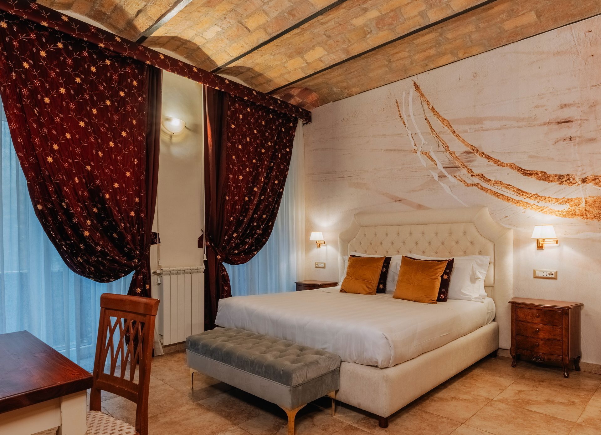 Schlafzimmer mit einem großen Bett, Samtvorhängen und einer dekorativen Wand.