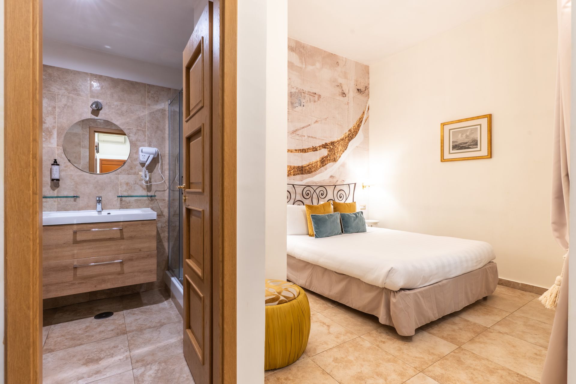 Hotelzimmer mit einsehbarem Badezimmer: Bett, Waschtisch, Dusche, neutrale Farben.