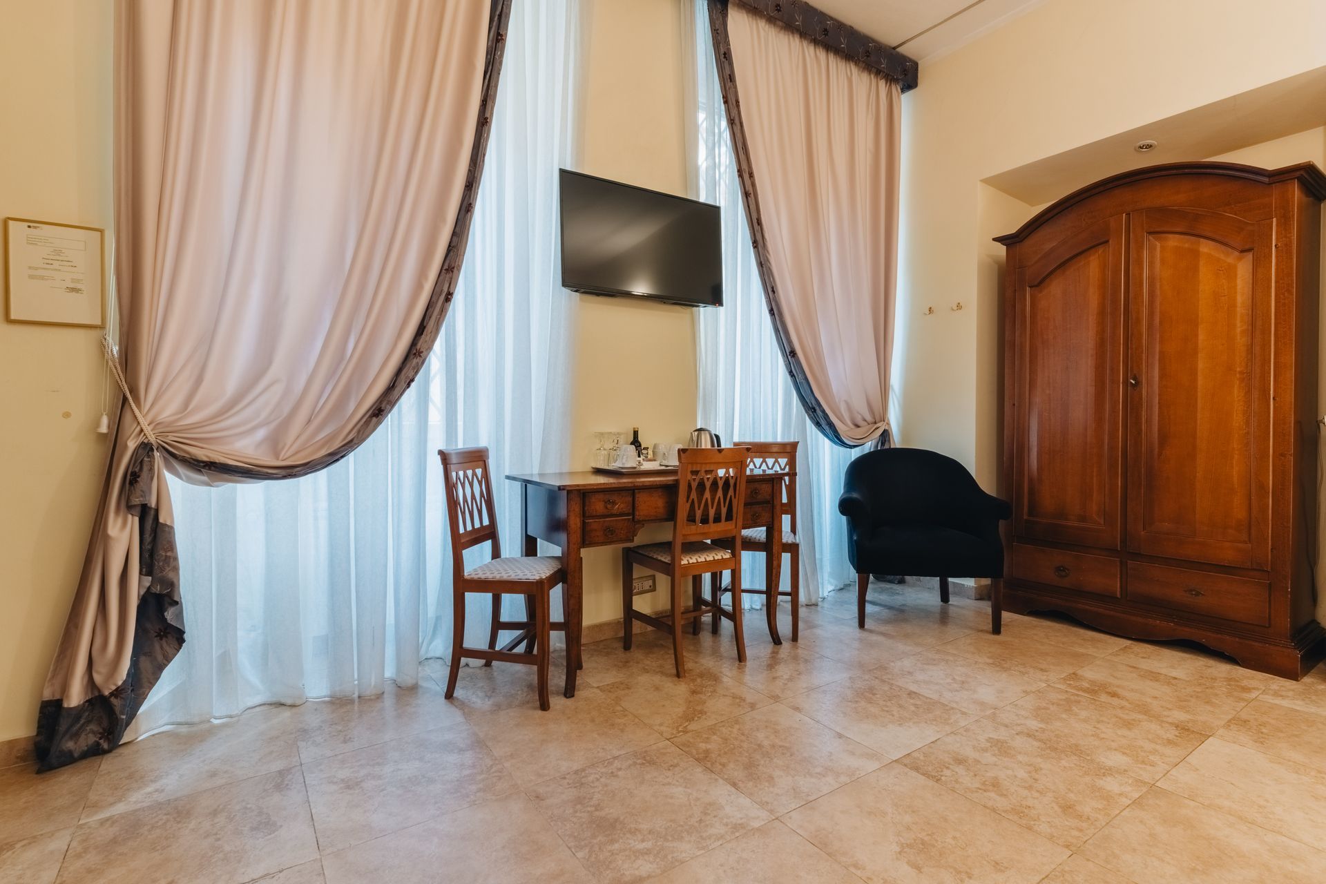 Zimmer mit verhängten Fenstern, Schreibtisch, Stühlen, Kleiderschrank und Fernseher.