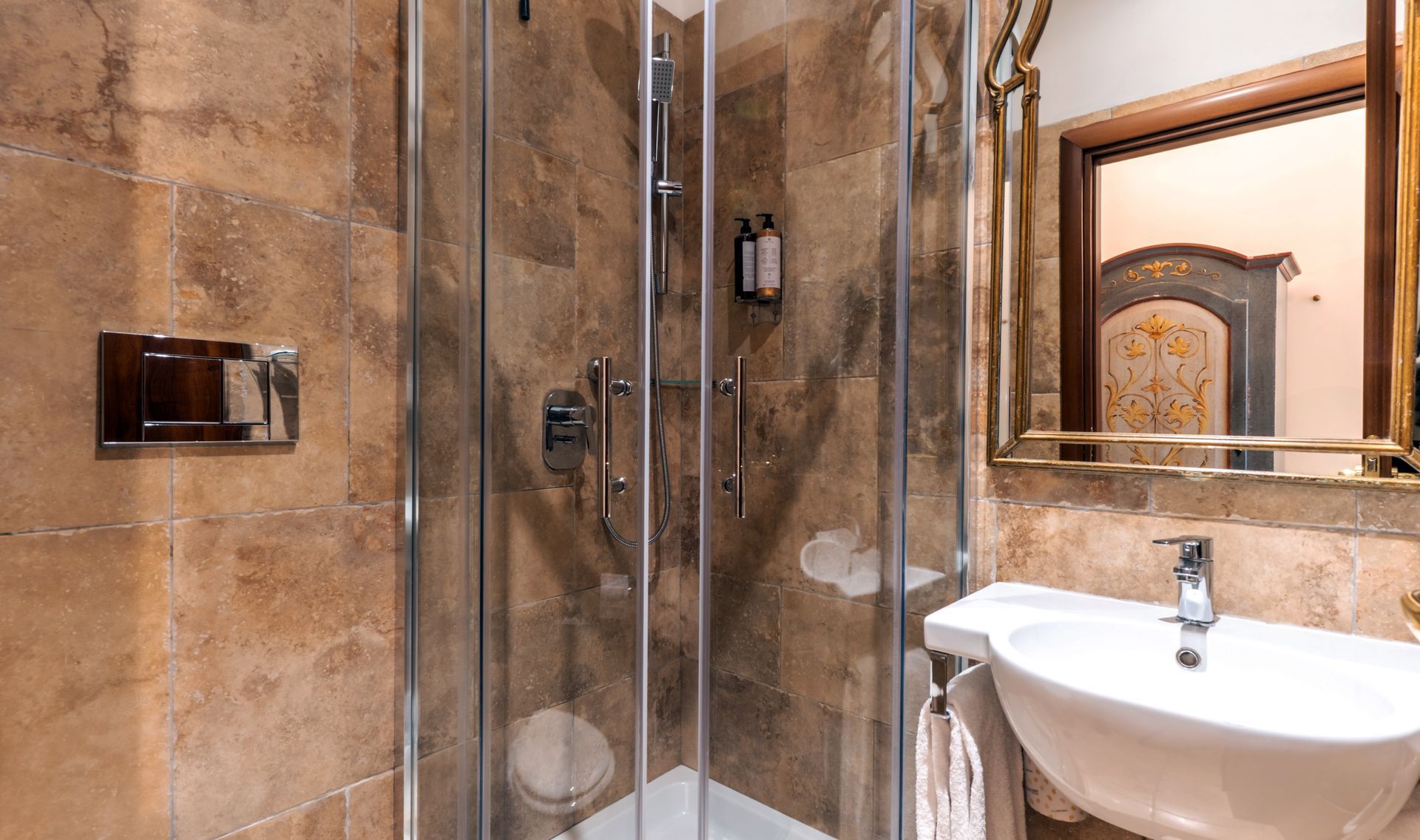 Kleines Badezimmer mit ebenerdiger Dusche, Waschbecken und Spiegel; Wände aus braunen Steinfliesen.