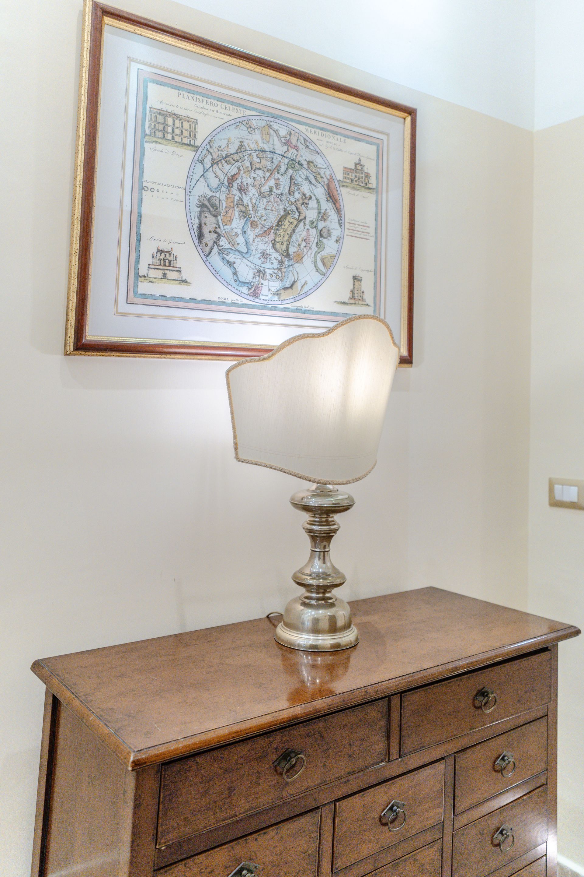 Holzkommode mit Lampe und gerahmter Landkarte.