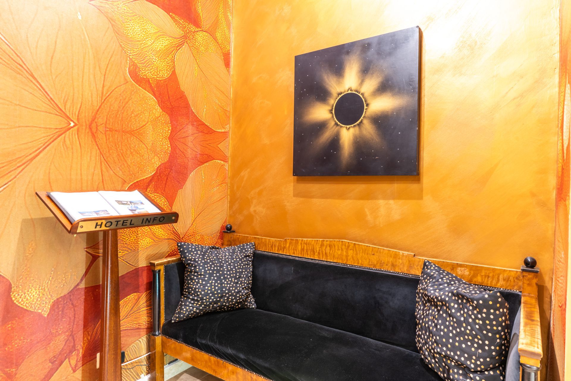 Gemütliche Ecke mit schwarzem Sofa, Zierkissen und orangefarbenen Wänden.