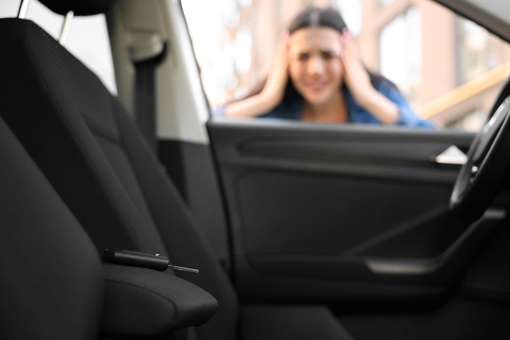 A woman looks distressed through a car window at keys left on the driver's seat.
