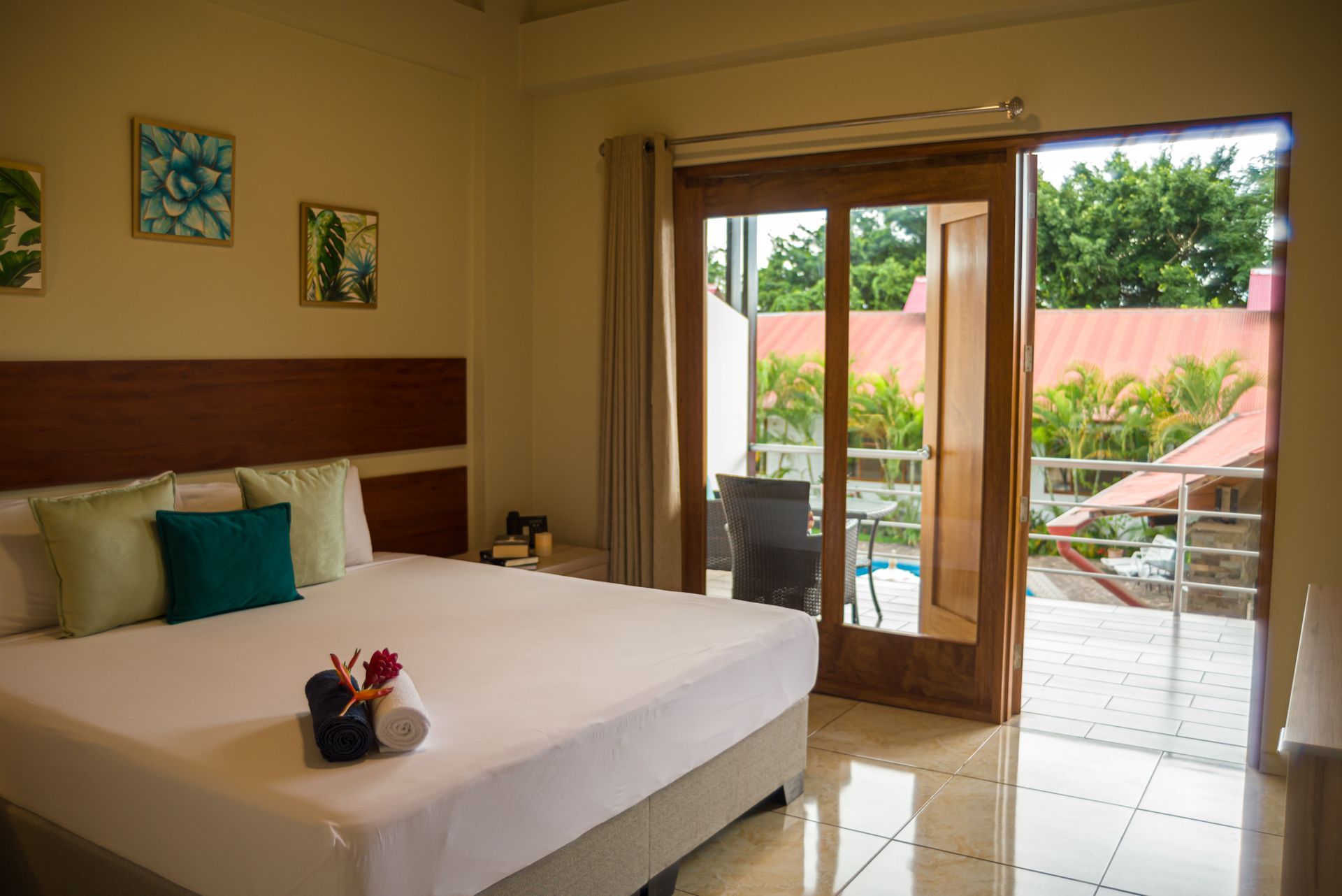 Dormitorio con cama, puerta abierta a balcón y obras de arte.