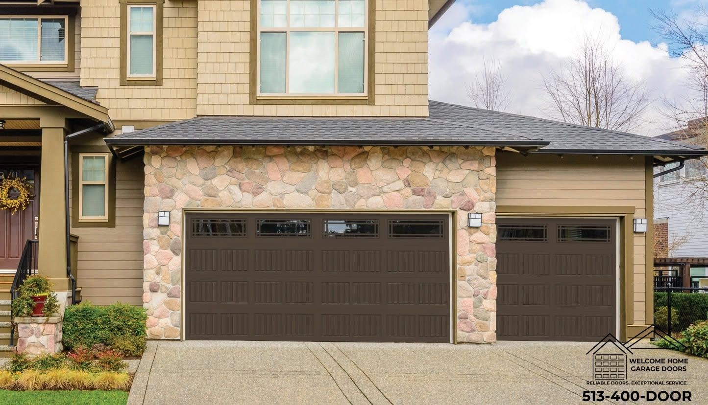 Suburban two-car garage with beige stone exterior, dark brown doors, and a paved driveway.