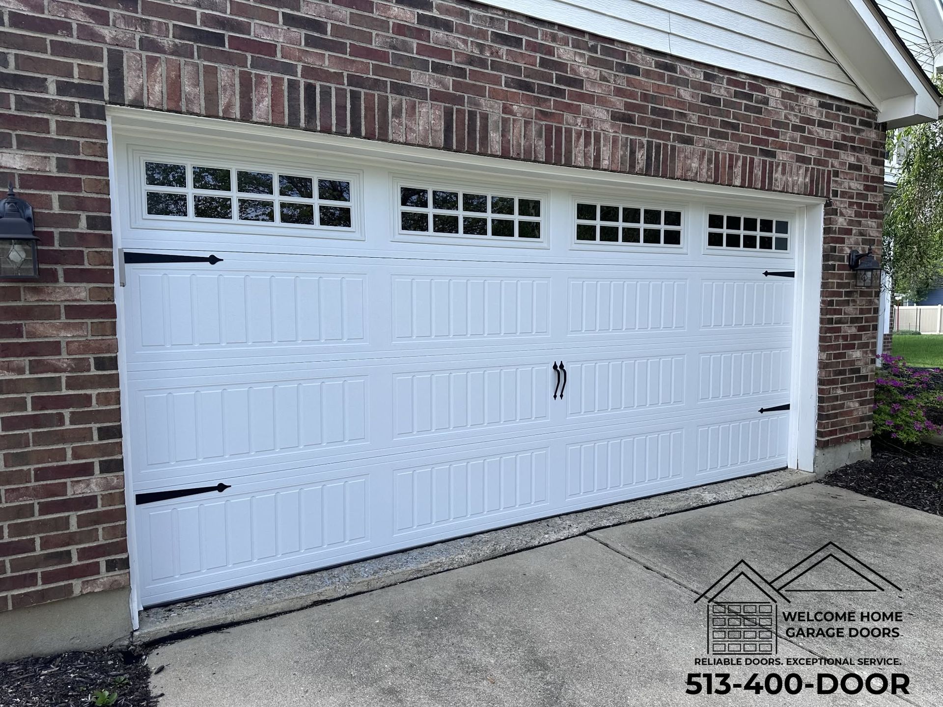 White garage door with small windows on a brick house and concrete driveway