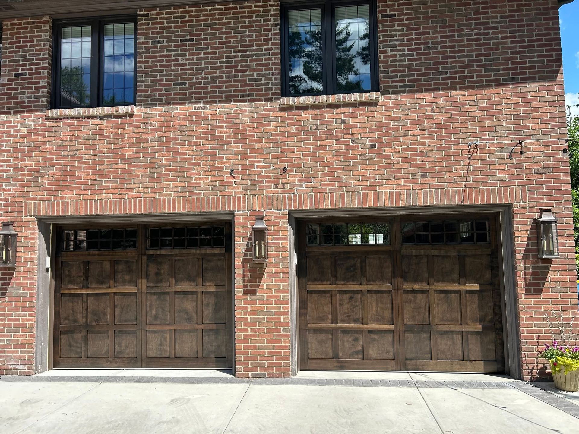 Brick house facade with two wooden garage doors and a concrete driveway