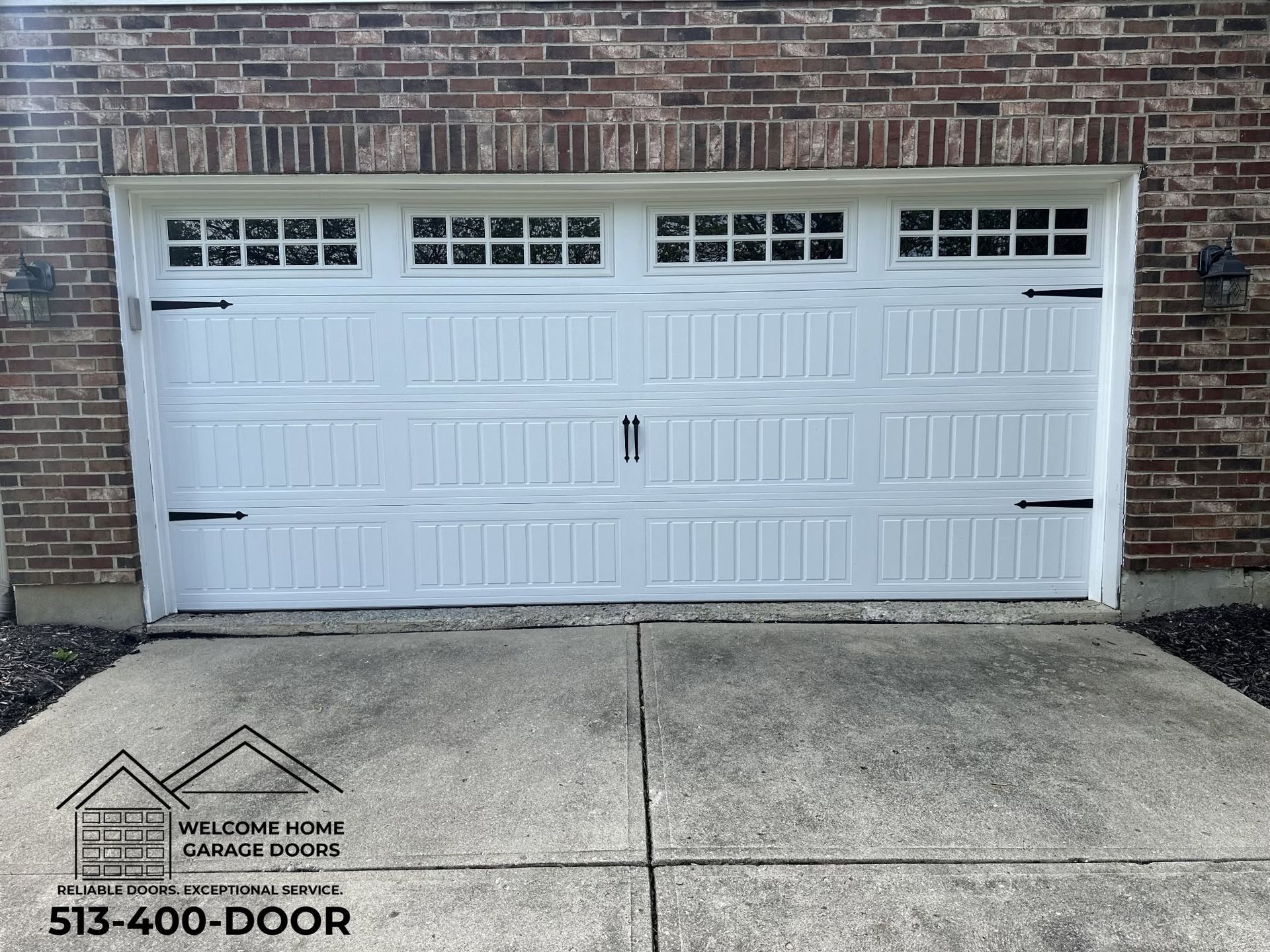 White double garage door with windows in a brick wall and concrete driveway