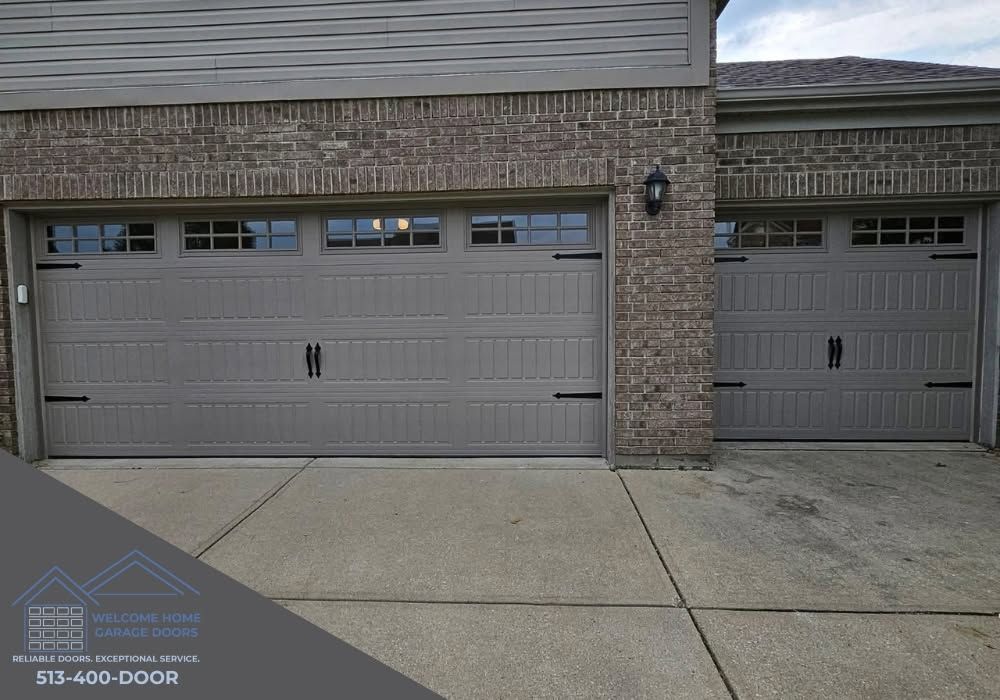 Two gray garage doors on a brick house with a concrete driveway