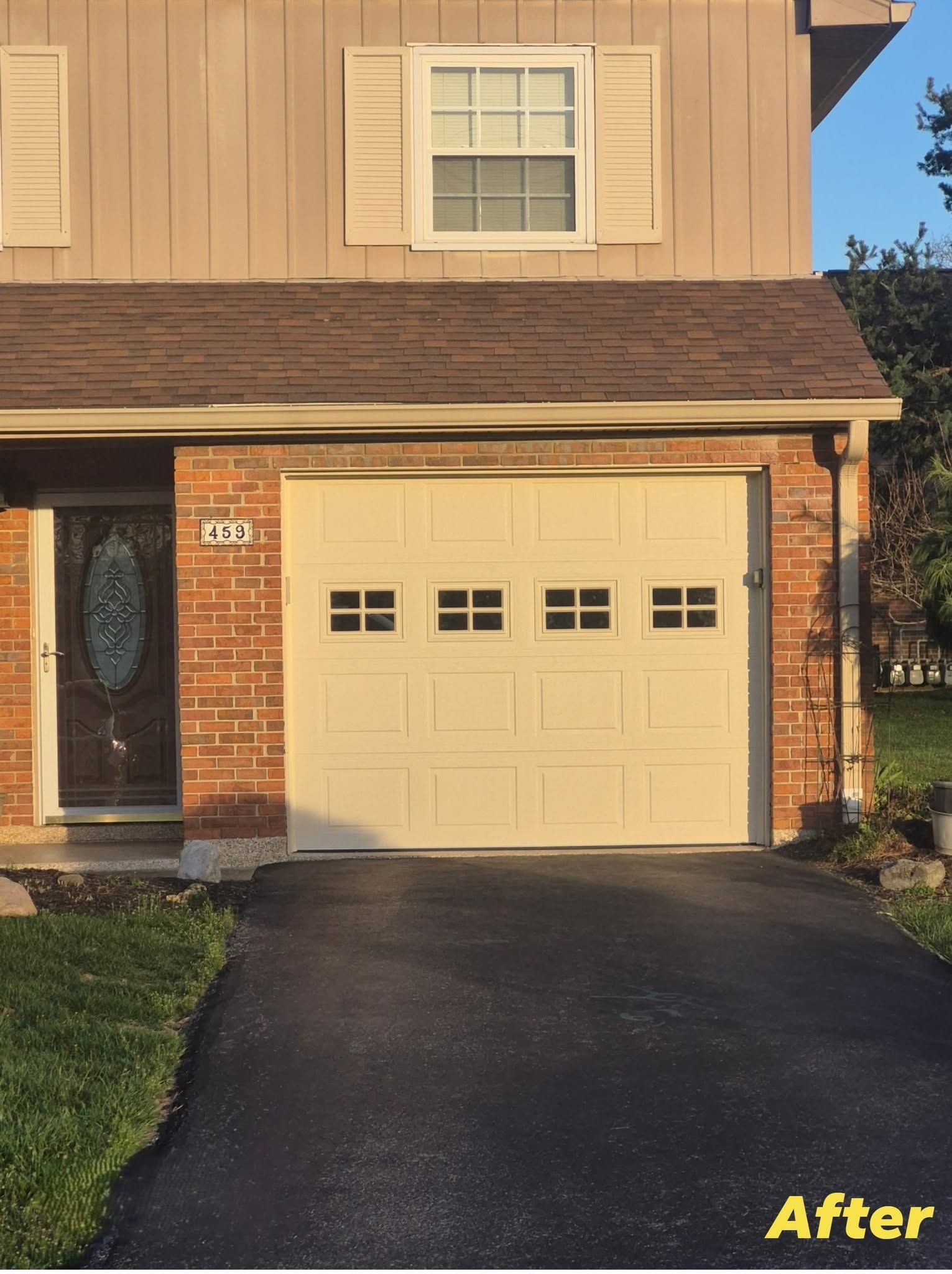 Two-story tan house with brick facade, single garage, and black driveway at sunset, labeled 