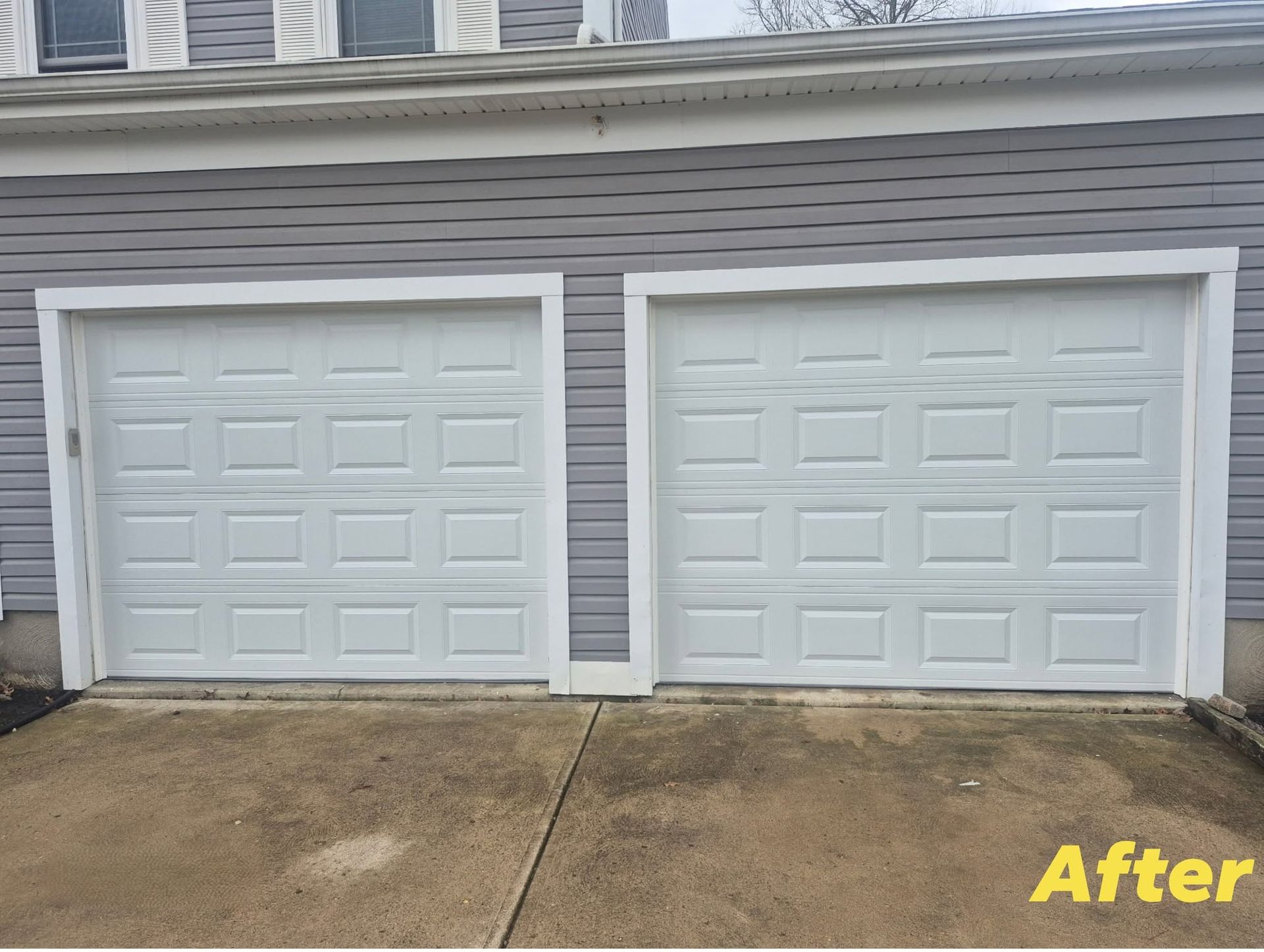 Two white paneled garage doors on a gray house exterior, labeled “After” in the corner.