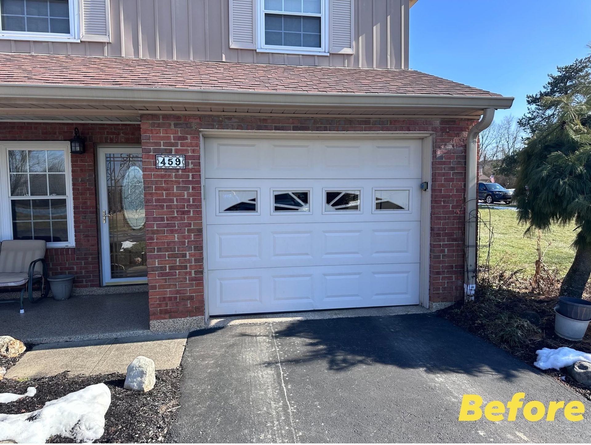 Brick house garage with white door and driveway, before view with some snow on the ground